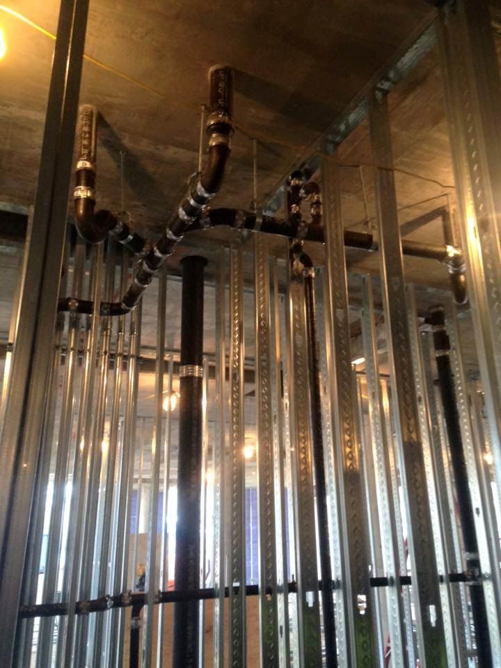 Metal framing with black pipes overhead; a construction site.