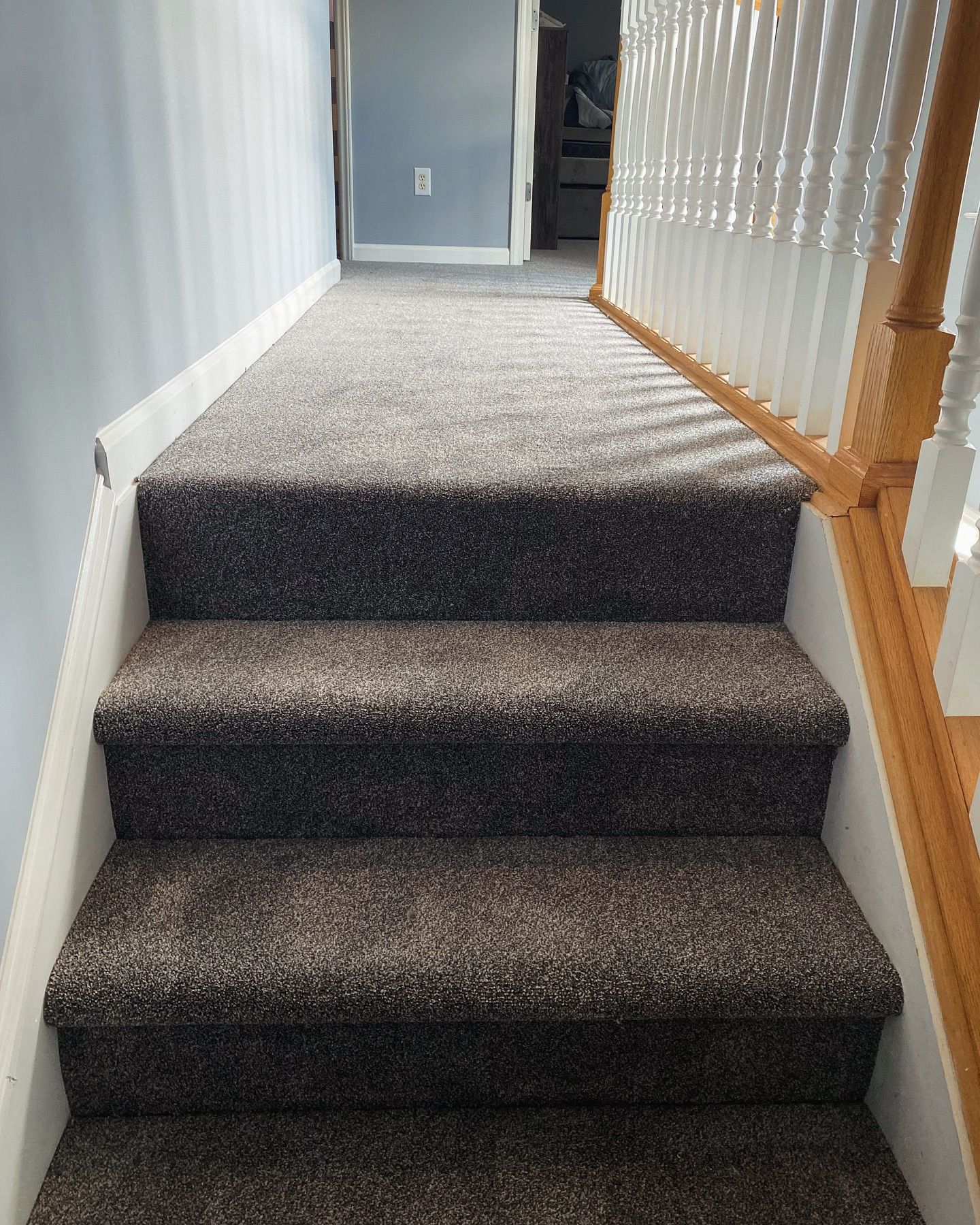 A staircase with a carpeted staircase and a wooden railing.