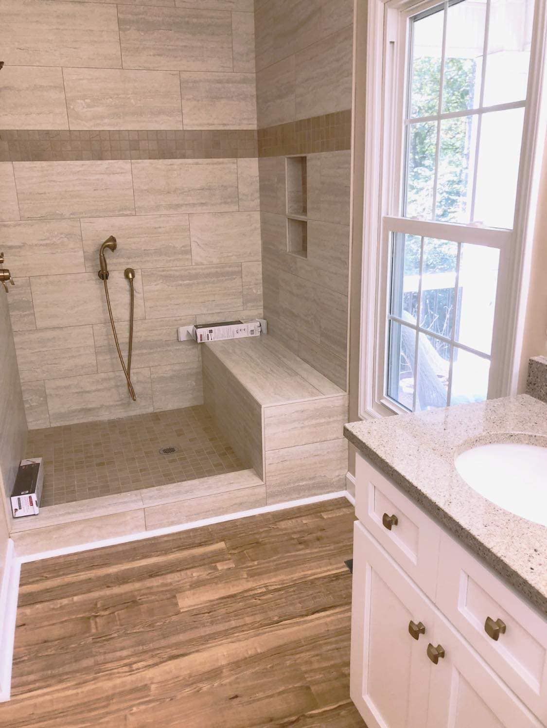 A bathroom with a walk in shower , sink , and window.