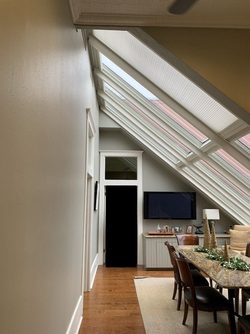 A dining room with a table and chairs under a skylight.