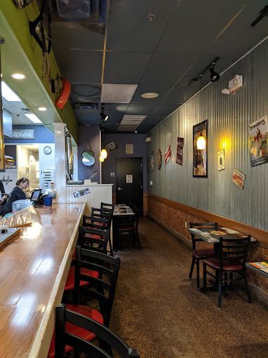 Interior of a restaurant with a bar, tables, and decorations on the wall.