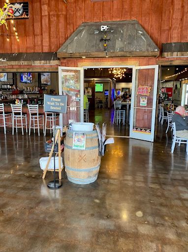Restaurant entrance with open doors, bar, seating, and a water barrel.