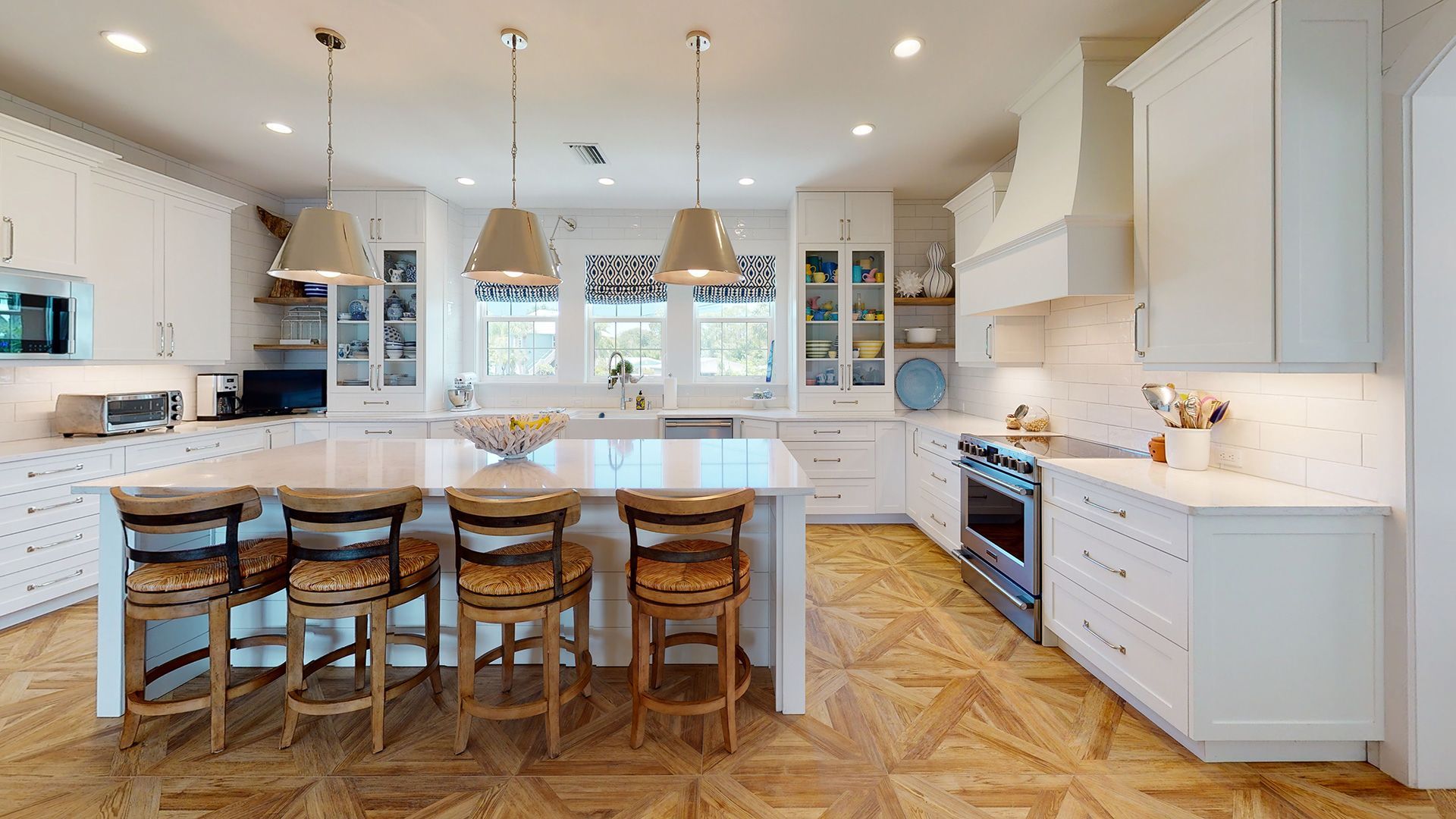 Bright white kitchen with a large island, wood floors, and pendant lights.