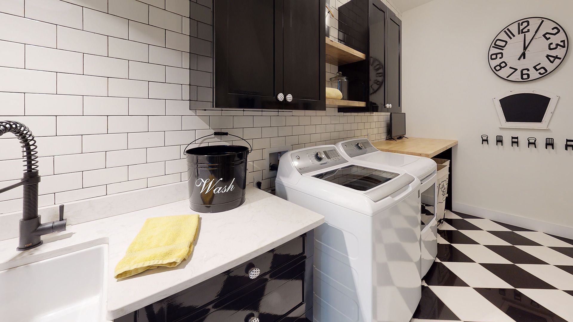 Laundry room with black and white tile, white appliances, and a black sink.