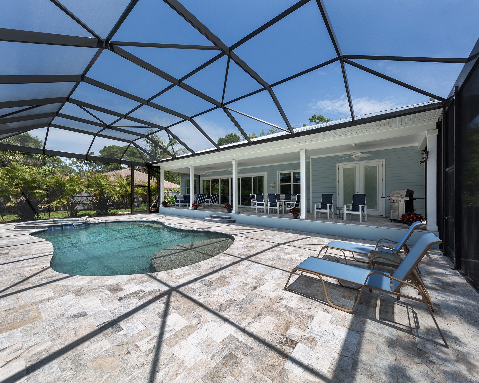 Pool and patio area with screened enclosure, lounge chairs, and a light blue house.