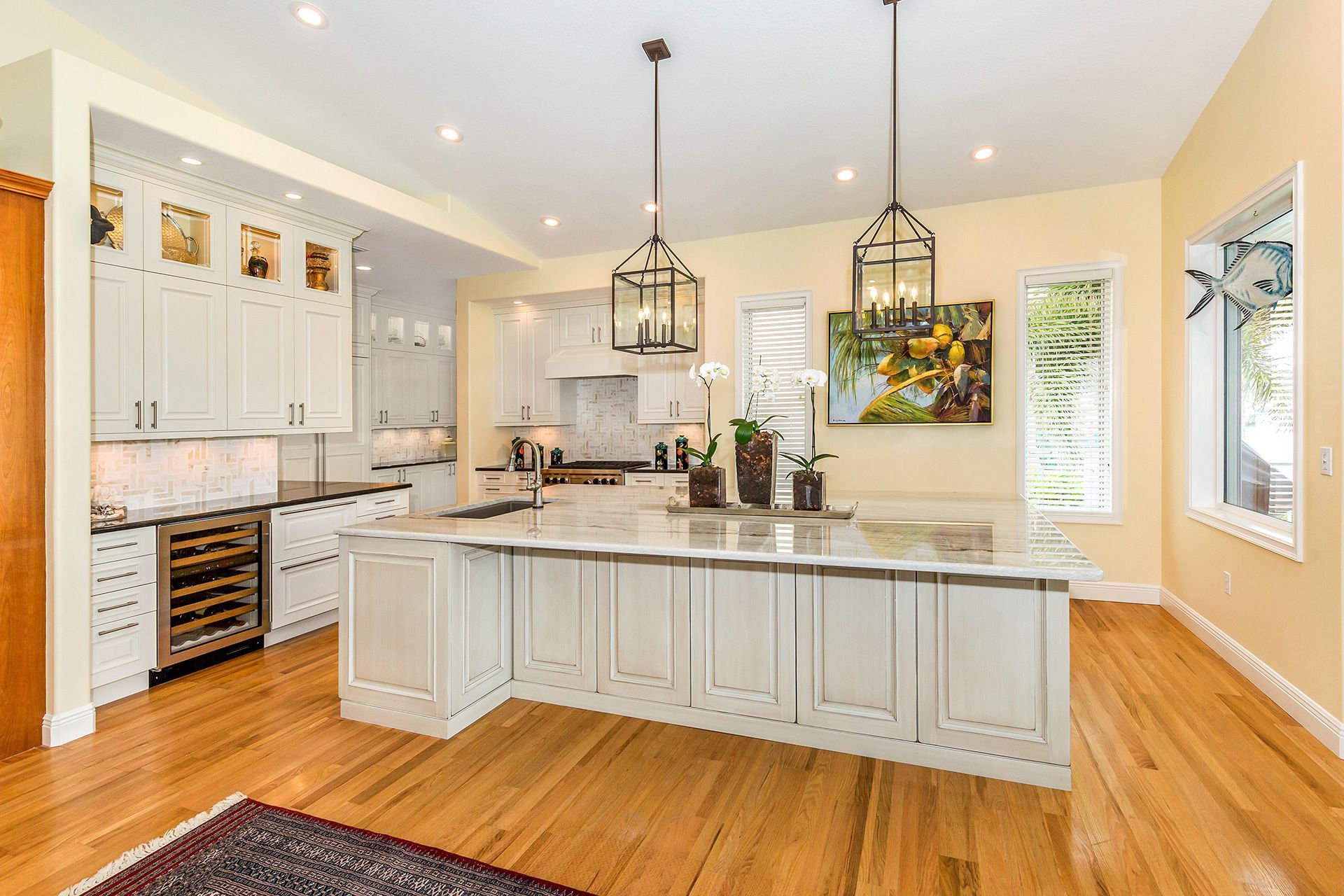 Spacious kitchen with a white island, wooden floors, and hanging lanterns.