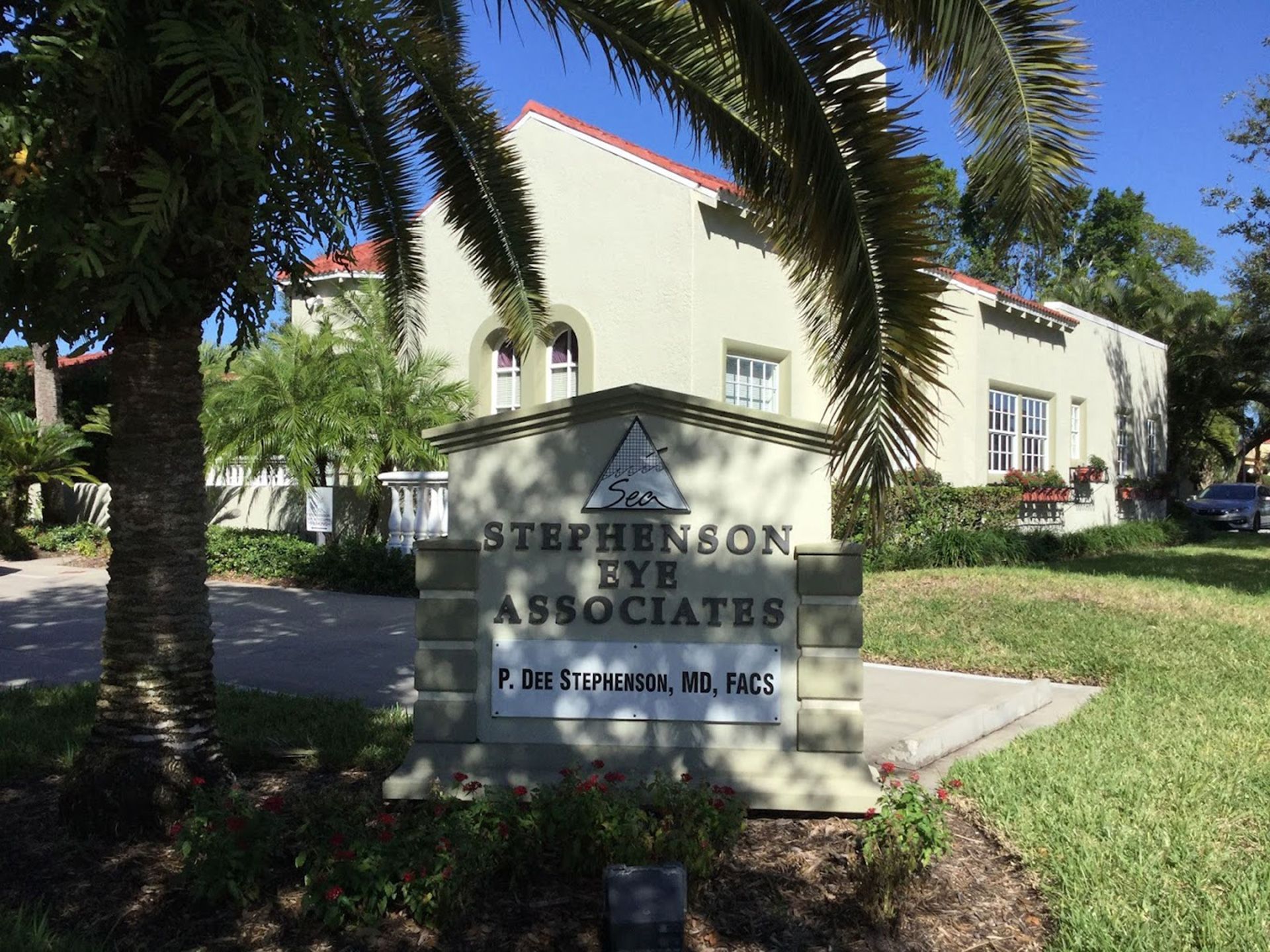 Sign for Stephenson Eye Associates in front of a light-colored building; palm trees and a sunny day.