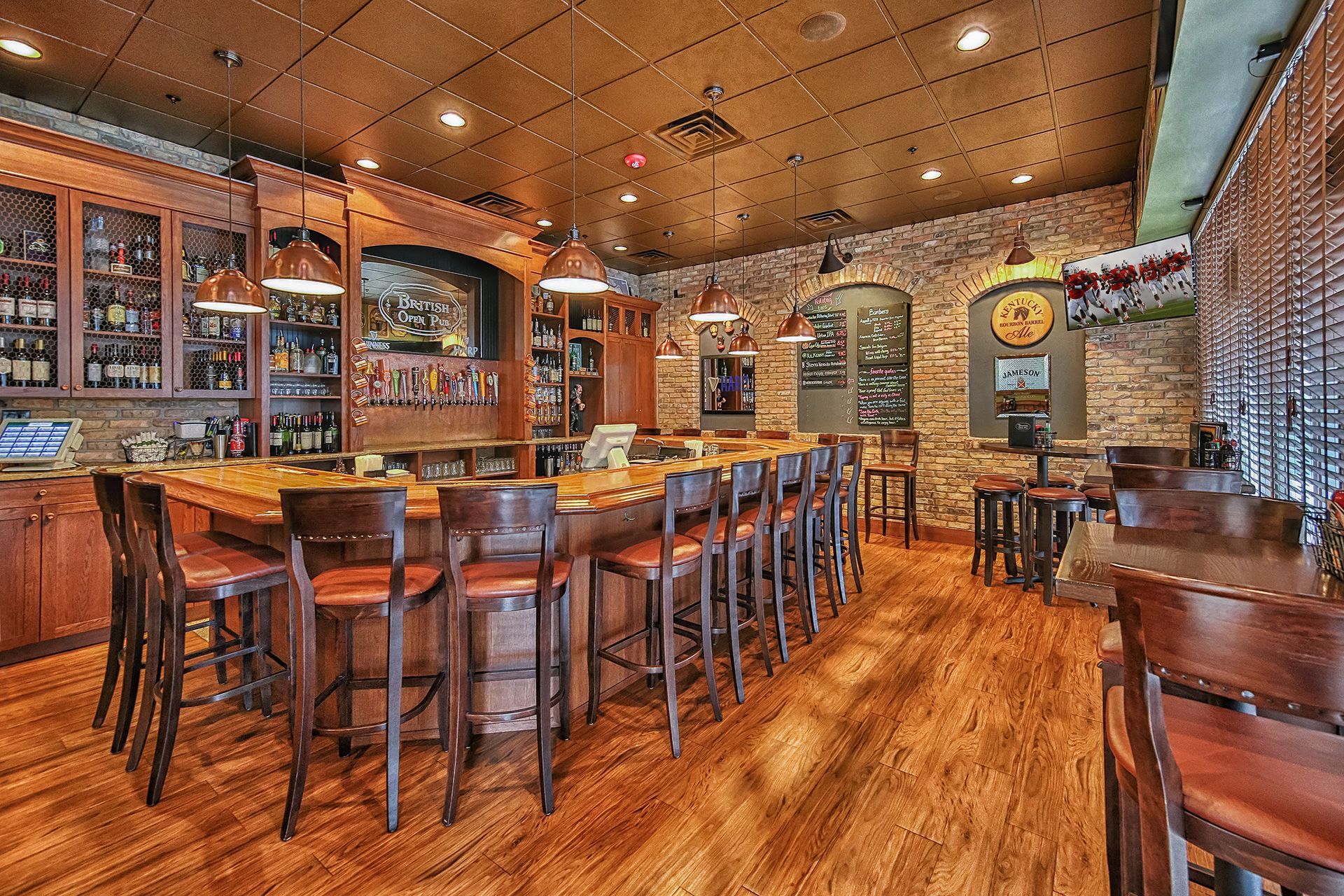 Bar interior with wooden floor, bar stools, and liquor shelves.