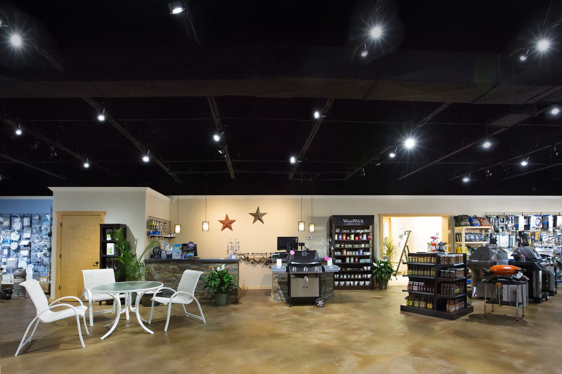 Interior of a retail store with grilling equipment, a seating area, and a dark ceiling.
