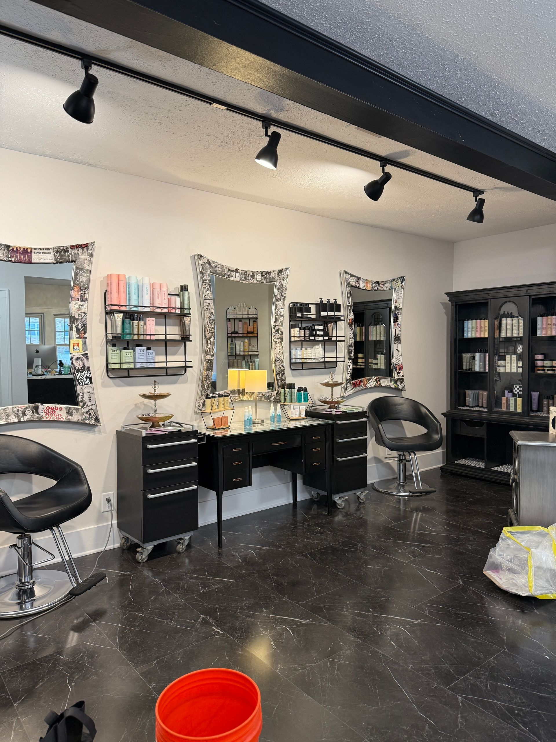 Modern salon interior with styling chairs, mirrors, counters, and black track lighting