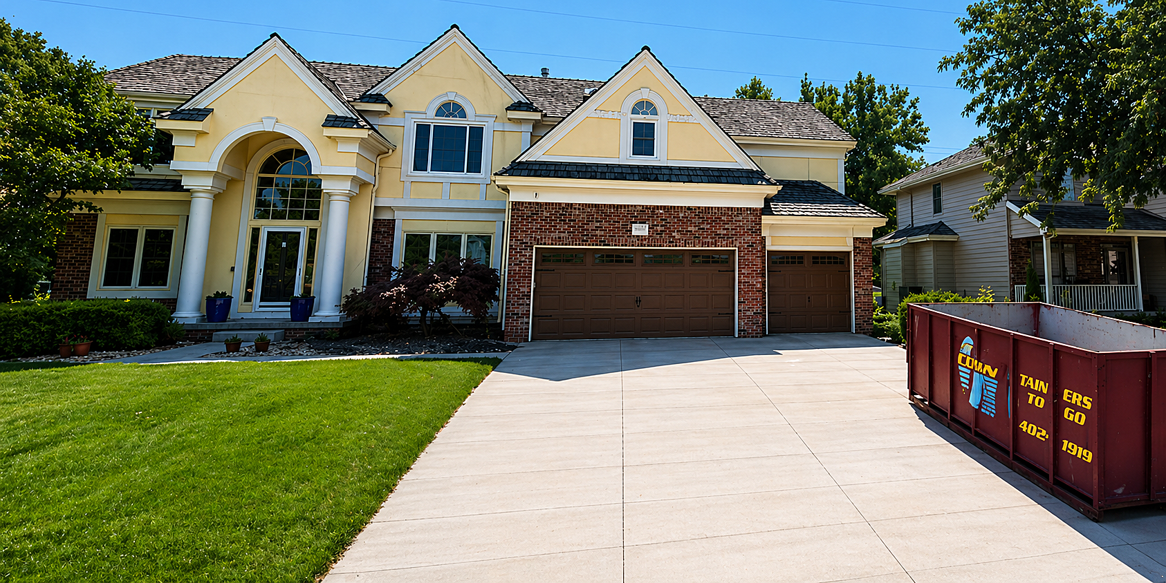 Suburban house with a wide driveway, green lawn, and a red dumpster at the curb