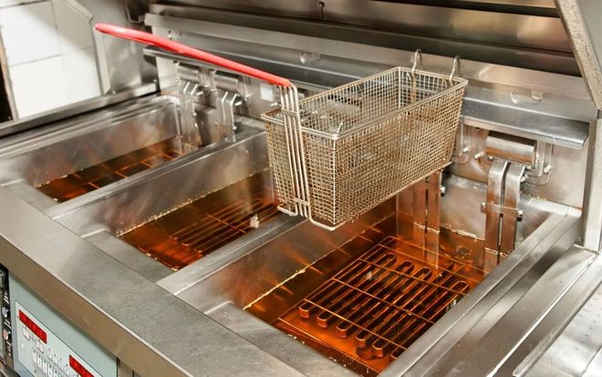 Commercial deep fryer with a basket, filled with oil.