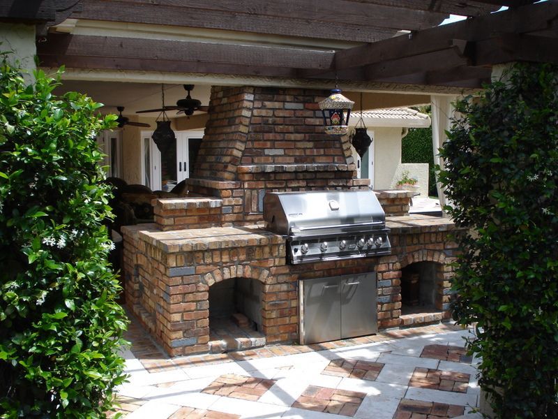 A brick outdoor kitchen with a stainless steel grill