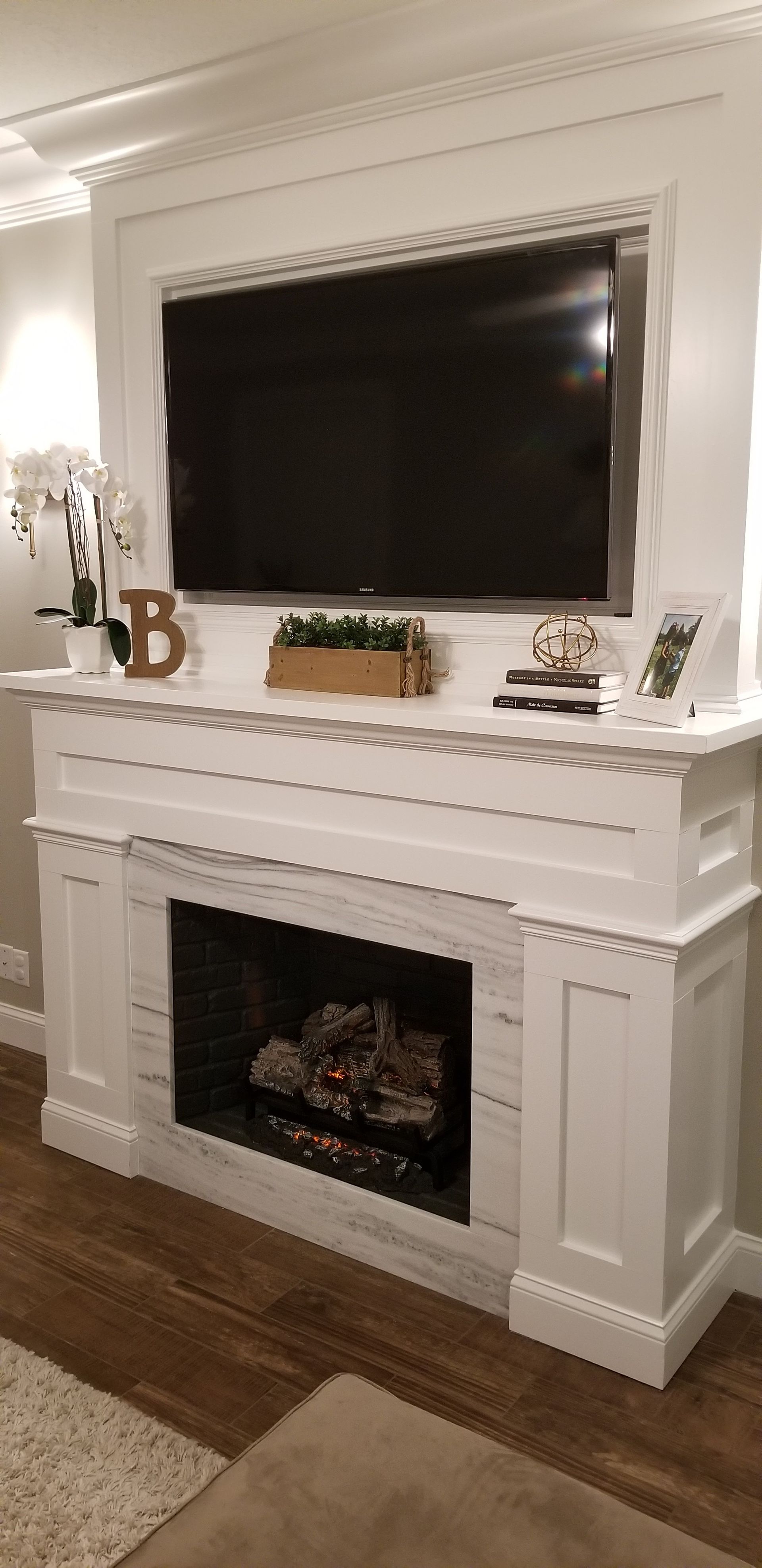 A living room with a fireplace and a flat screen tv on the wall.