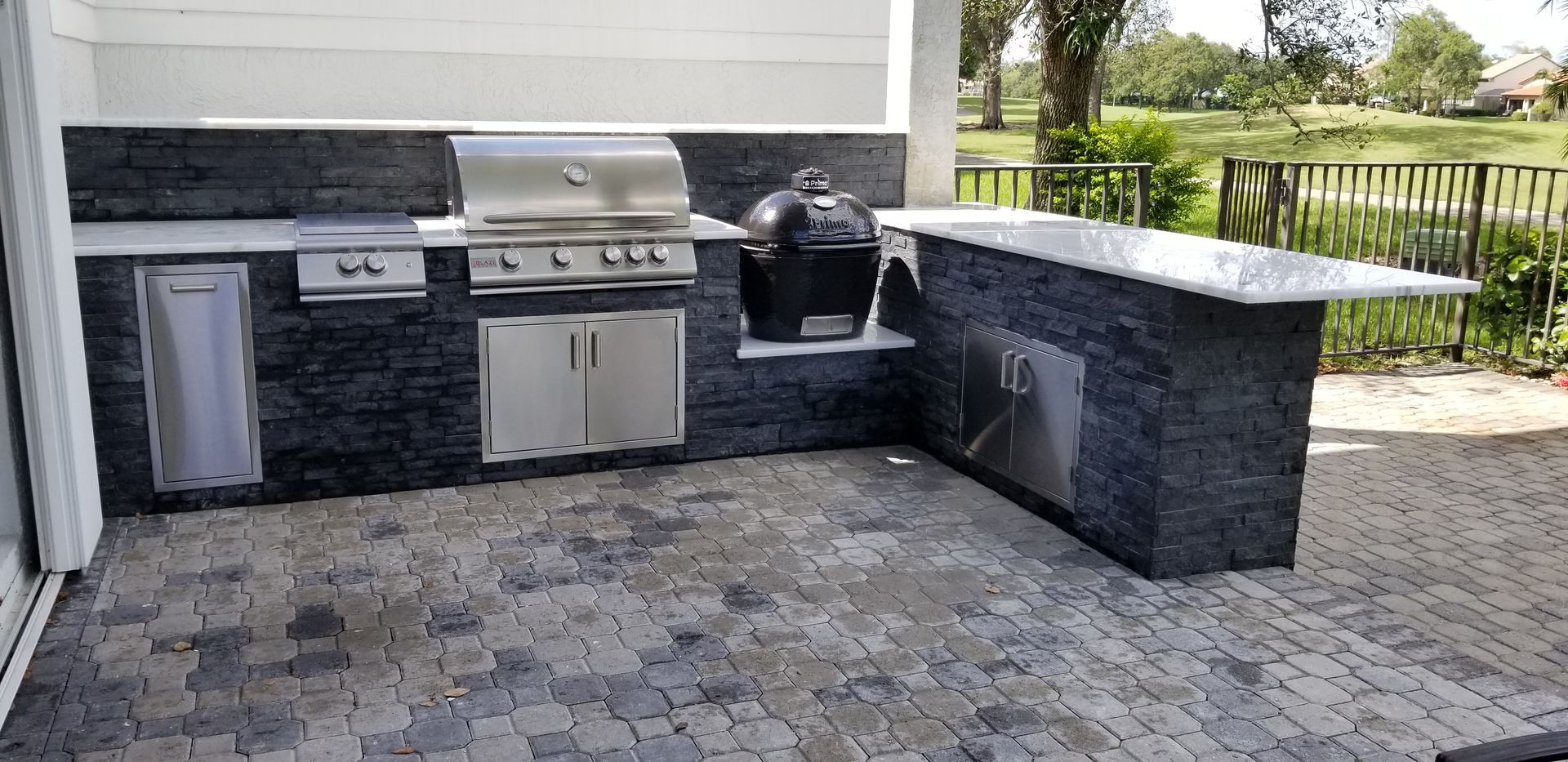 An outdoor kitchen with a grill , sink , and counter top.