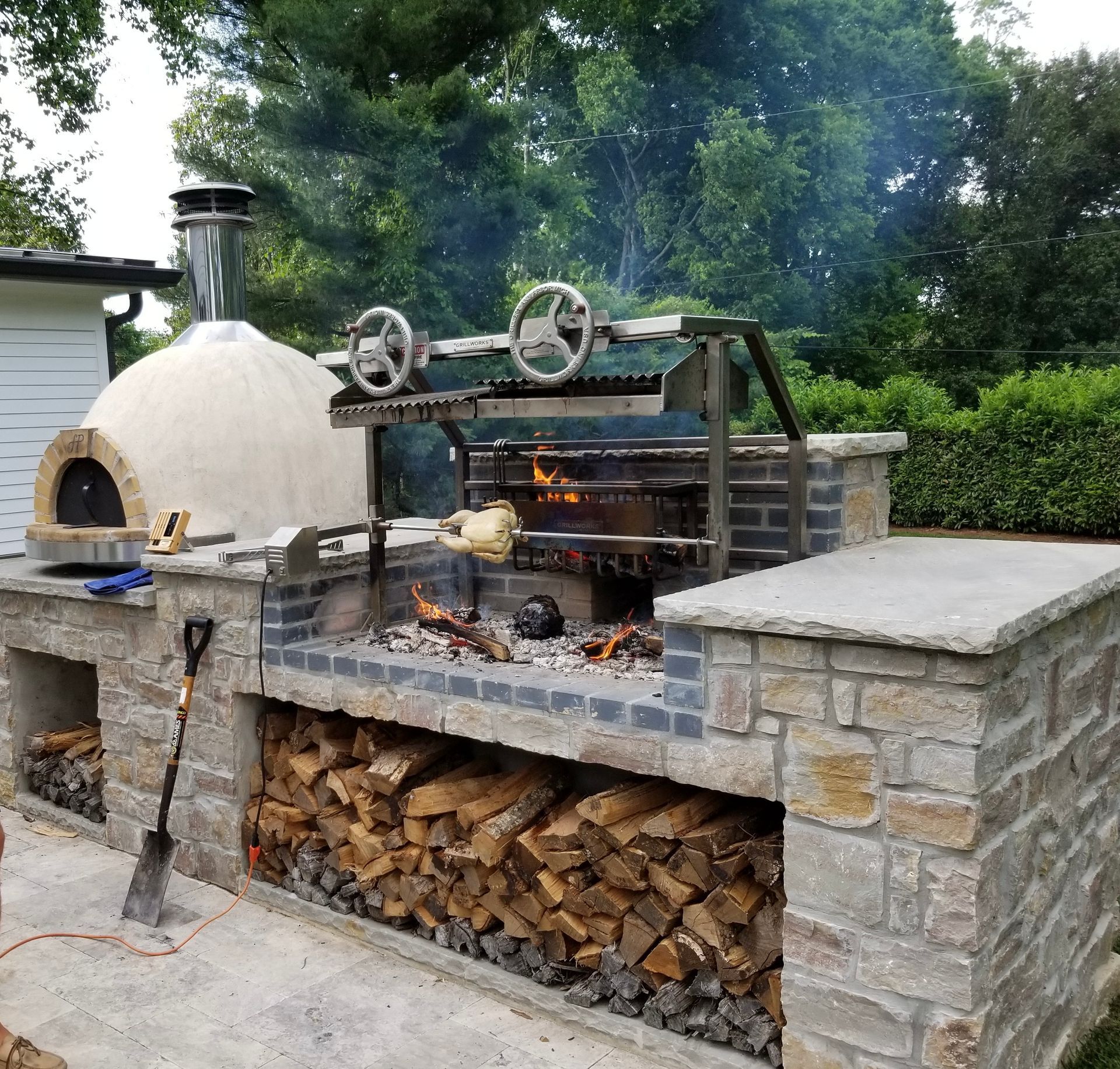 Custom-built stone barbecue with wood storage and pizza oven in Delray Beach, FL.