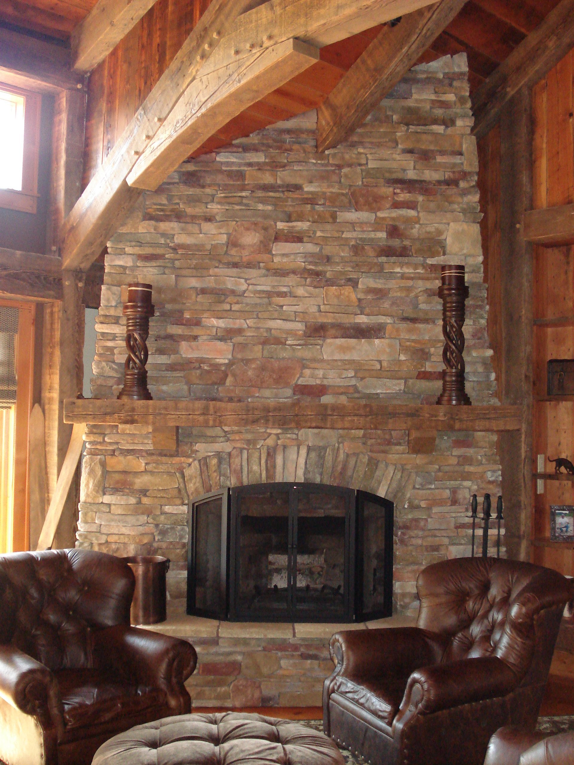 A living room with a stone fireplace and leather chairs
