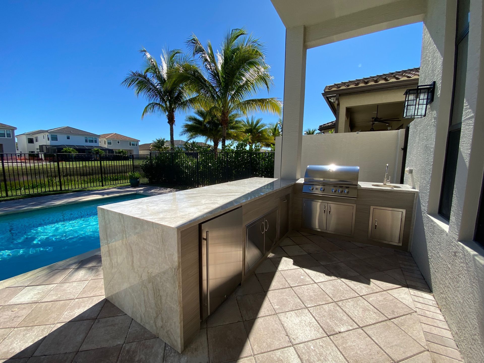 A patio with a grill and a swimming pool in the background