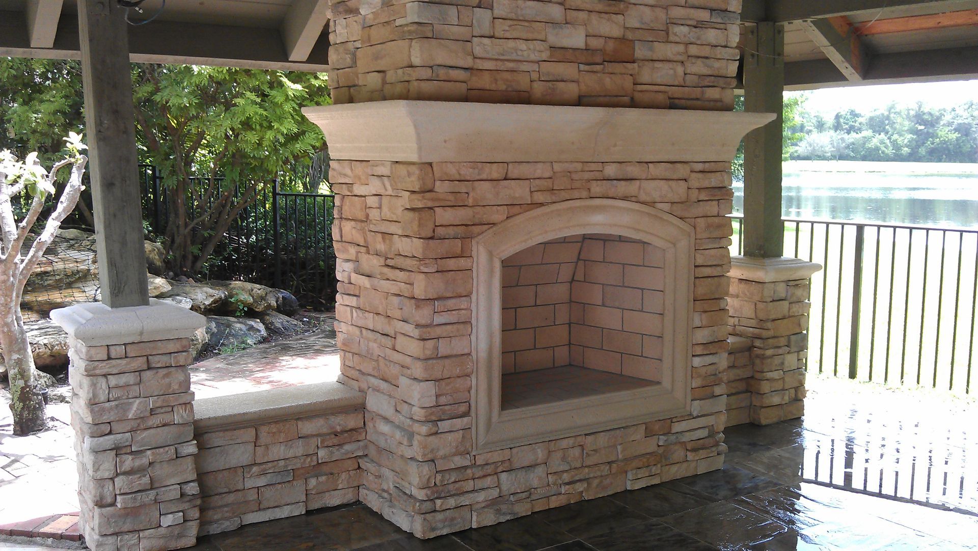 A stone fireplace with a view of a lake in the background