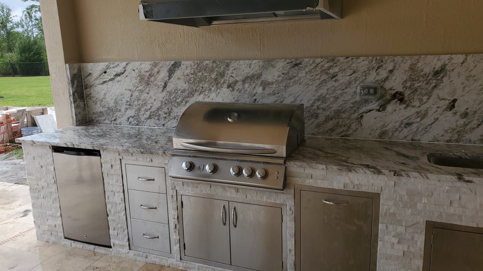 A stainless steel grill is sitting on top of a granite counter top.
