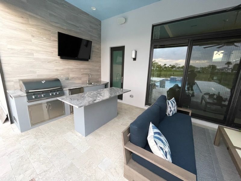 A patio with a grill , couch , and television.