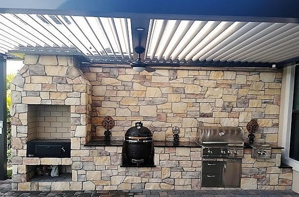 An outdoor kitchen with a brick wall and a grill.
