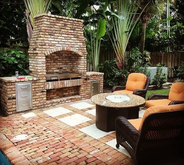 Brick outdoor kitchen and fireplace with seating area in Deerfield Beach, FL.