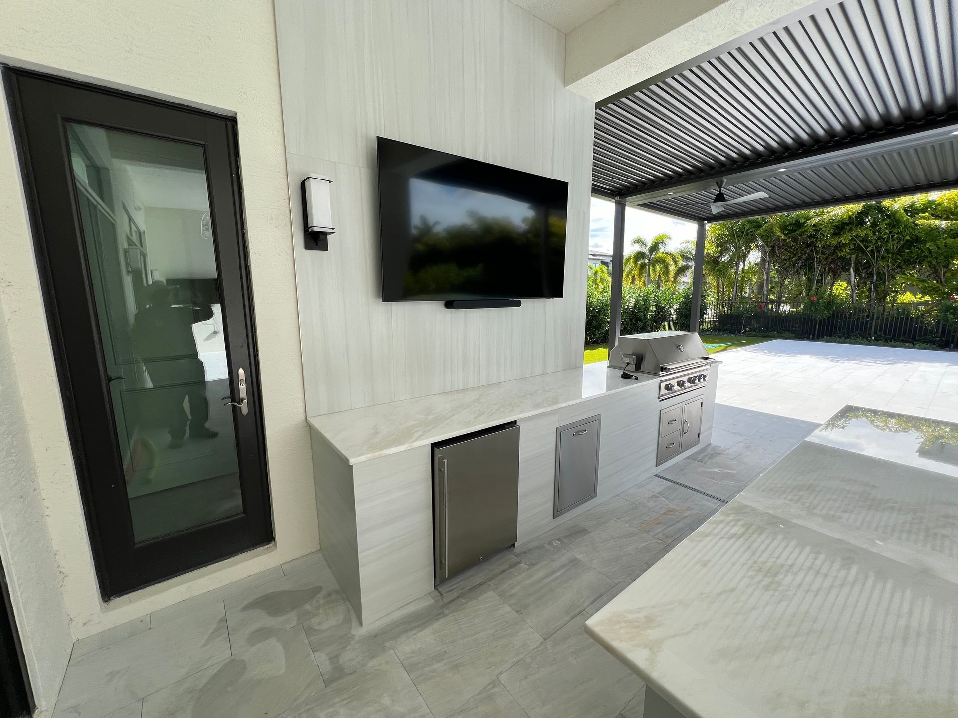 A large flat screen tv is mounted on the wall above a kitchen.