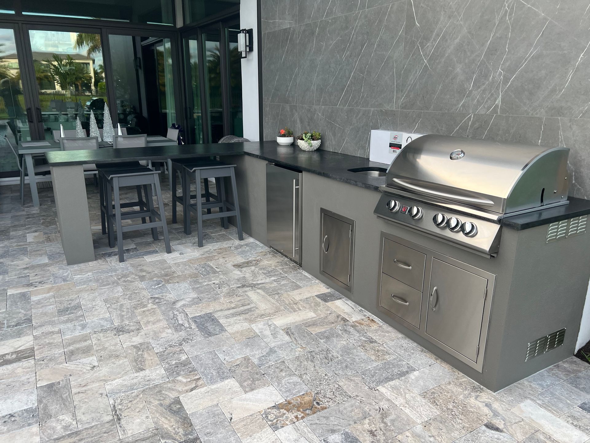 A large outdoor kitchen with a grill and a table and chairs.
