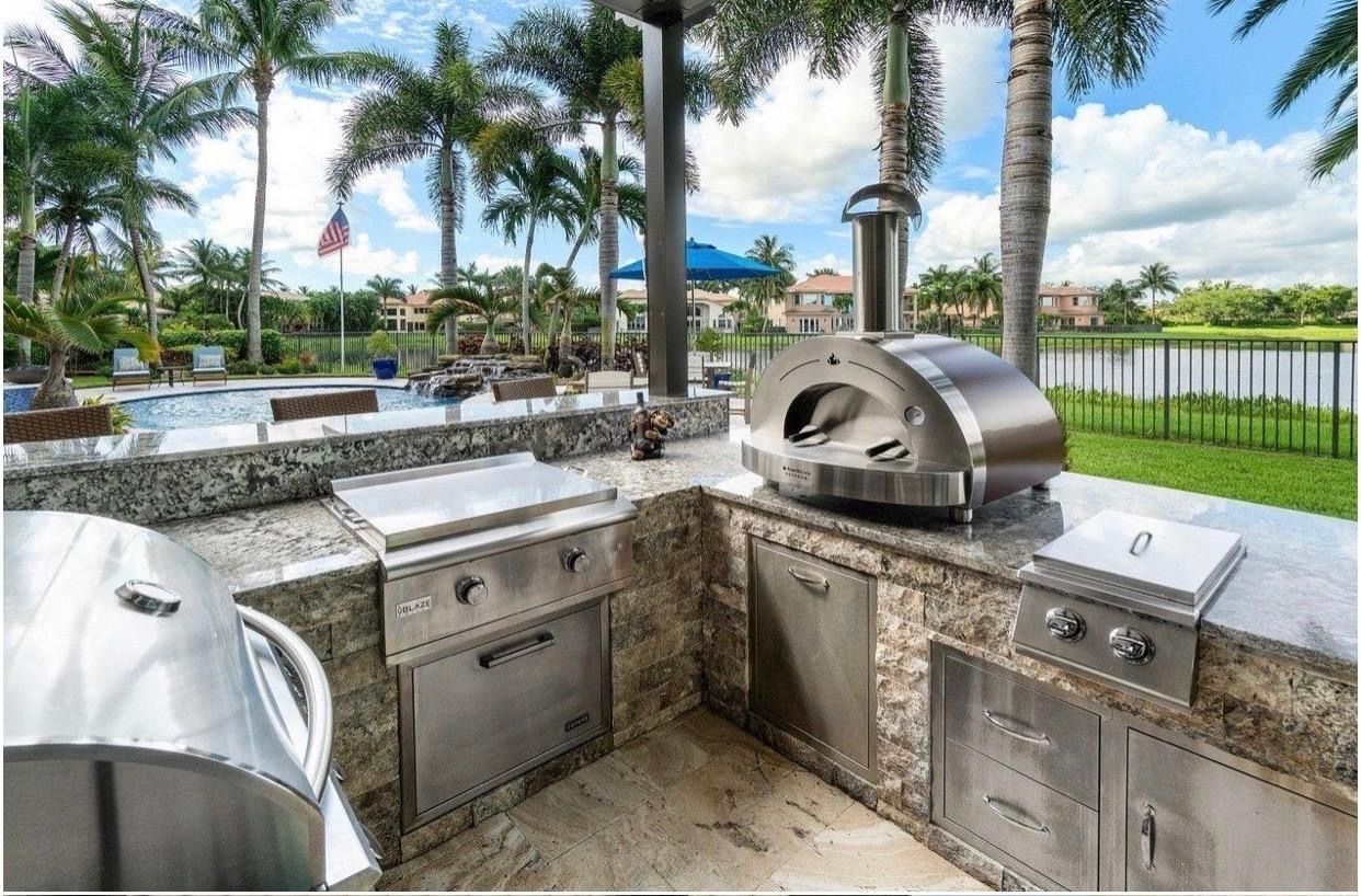 A stainless steel outdoor kitchen with a pizza oven and a grill.