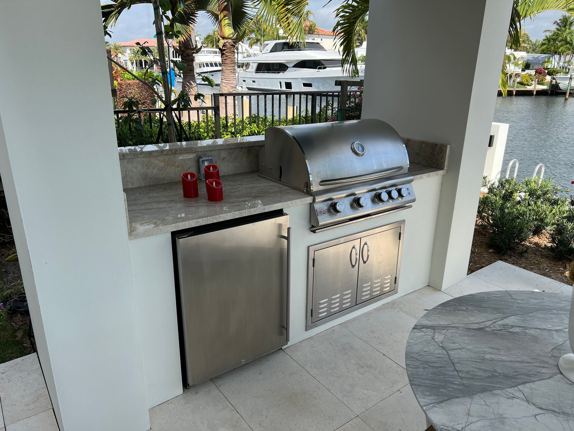 An outdoor kitchen with a grill and a refrigerator