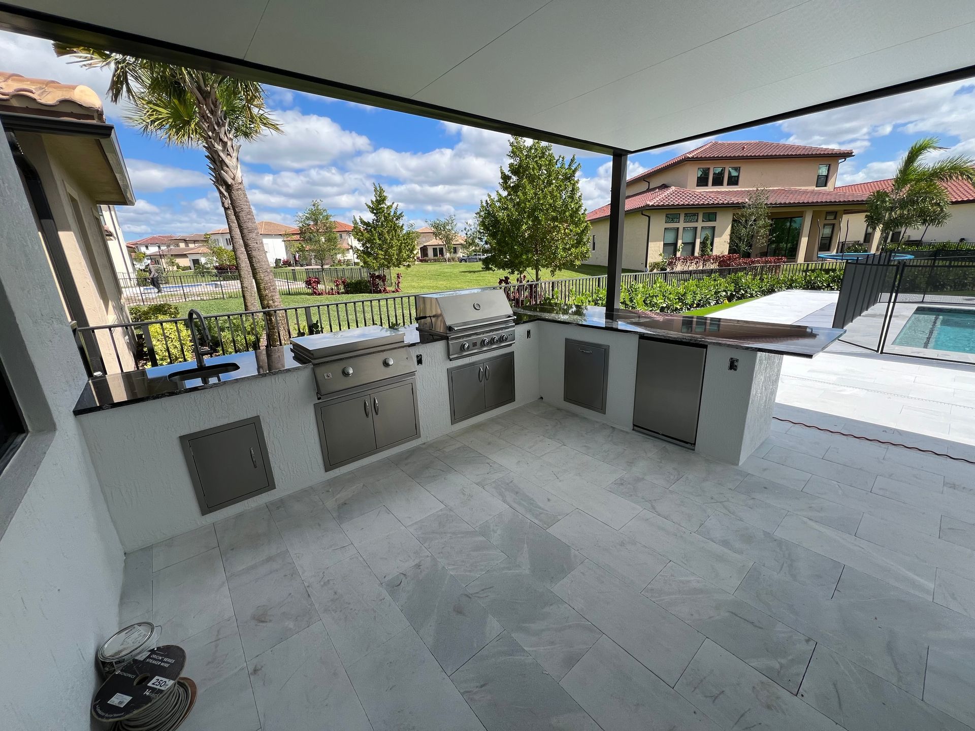A large outdoor kitchen with stainless steel appliances and a covered patio.