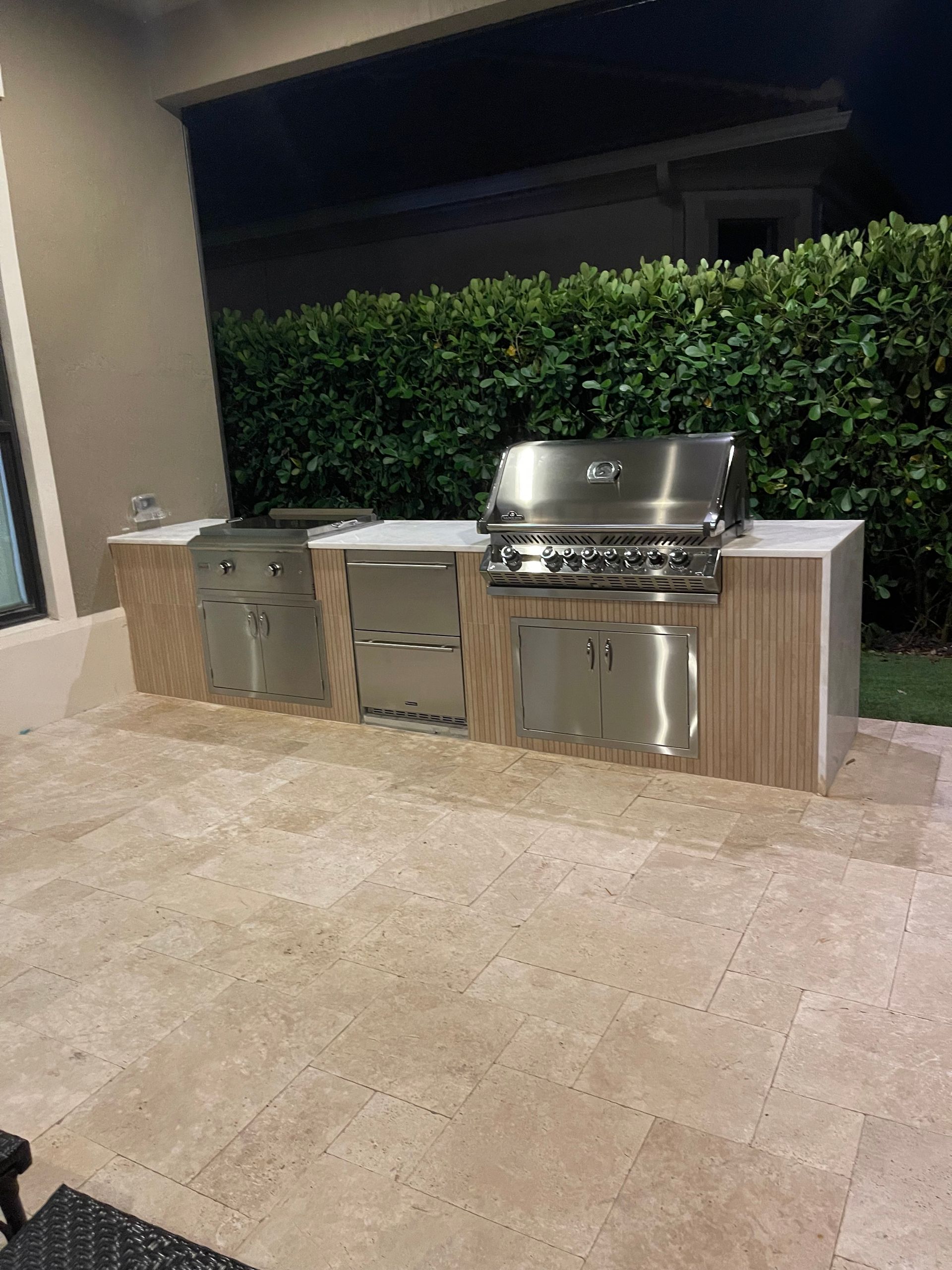 A large outdoor kitchen with stainless steel appliances and wooden cabinets.
