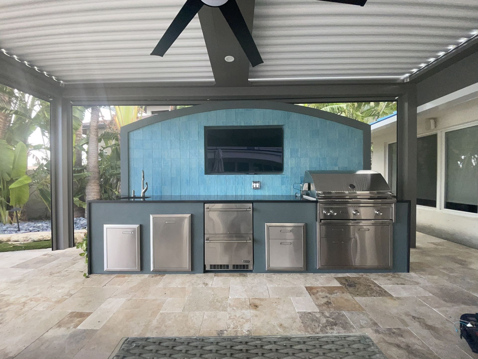 Outdoor kitchen with ceiling fan and modern appliances in Boynton Beach, FL.