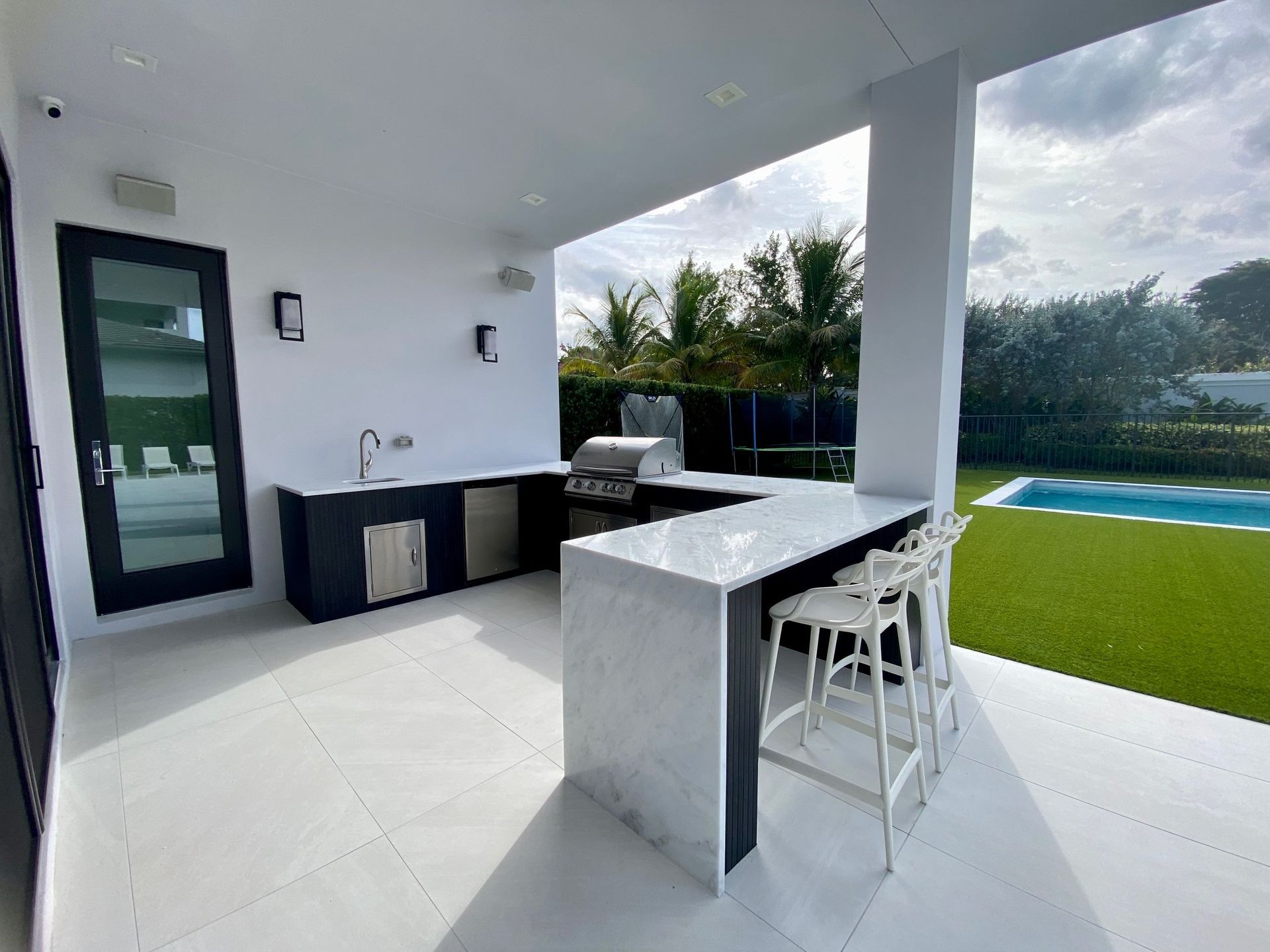 A kitchen with a grill and a swimming pool in the background