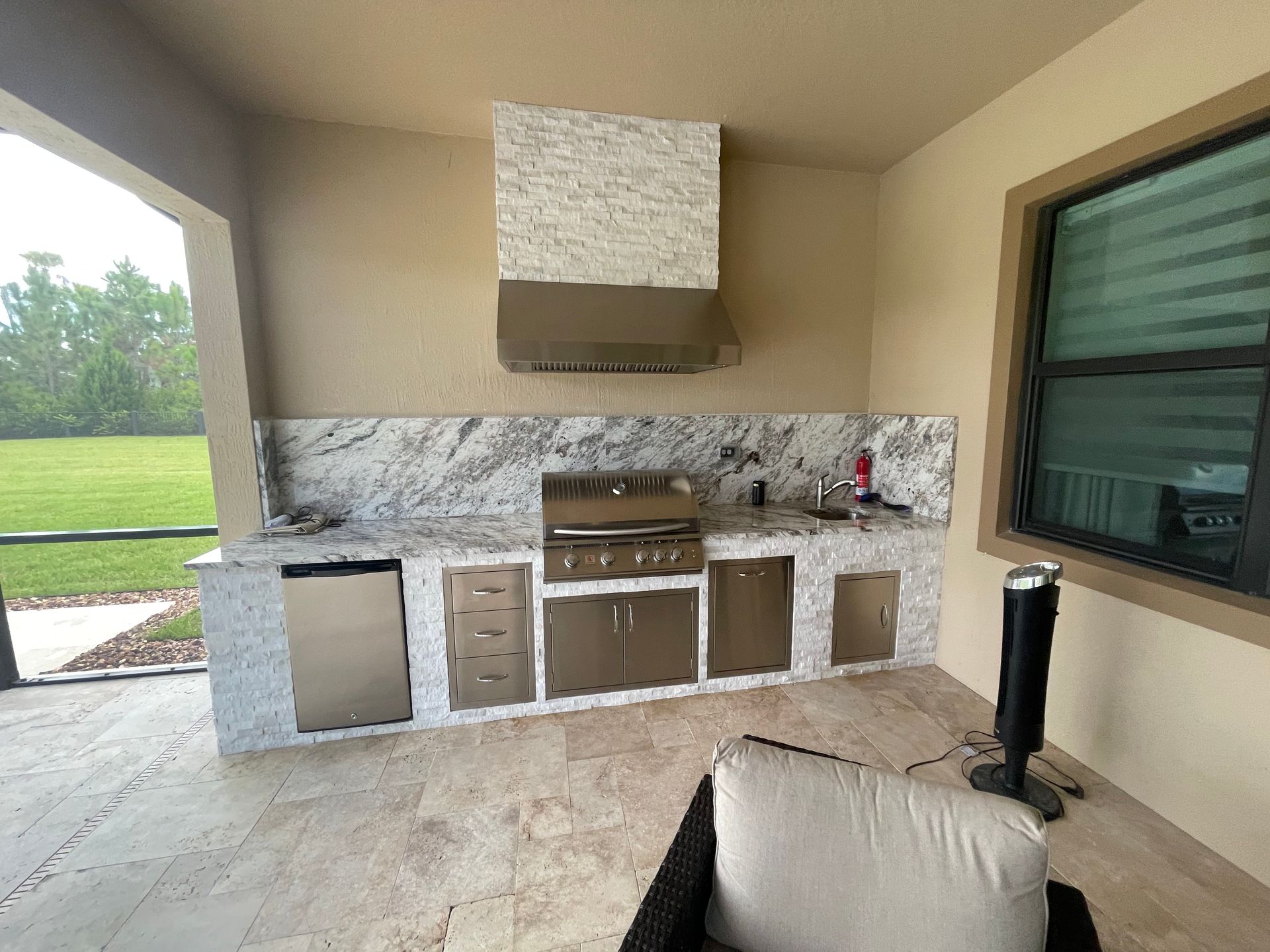 A large outdoor kitchen with a grill and a hood.