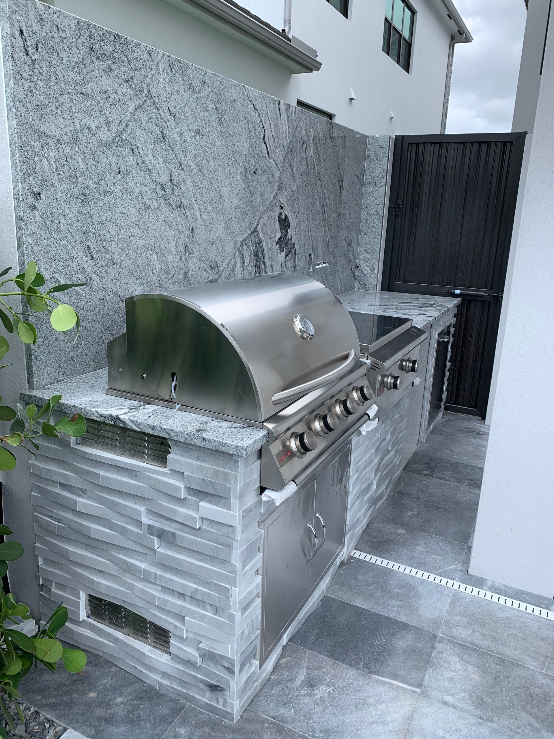 An outdoor kitchen with a stainless steel grill and granite counter tops.