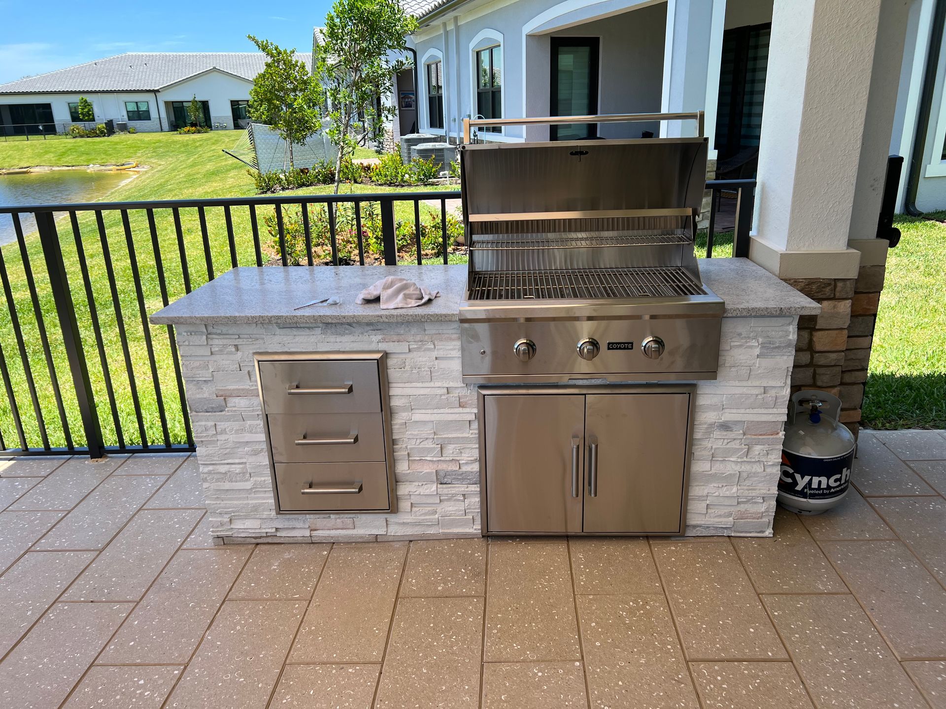 A stainless steel grill is sitting on a patio in front of a house.