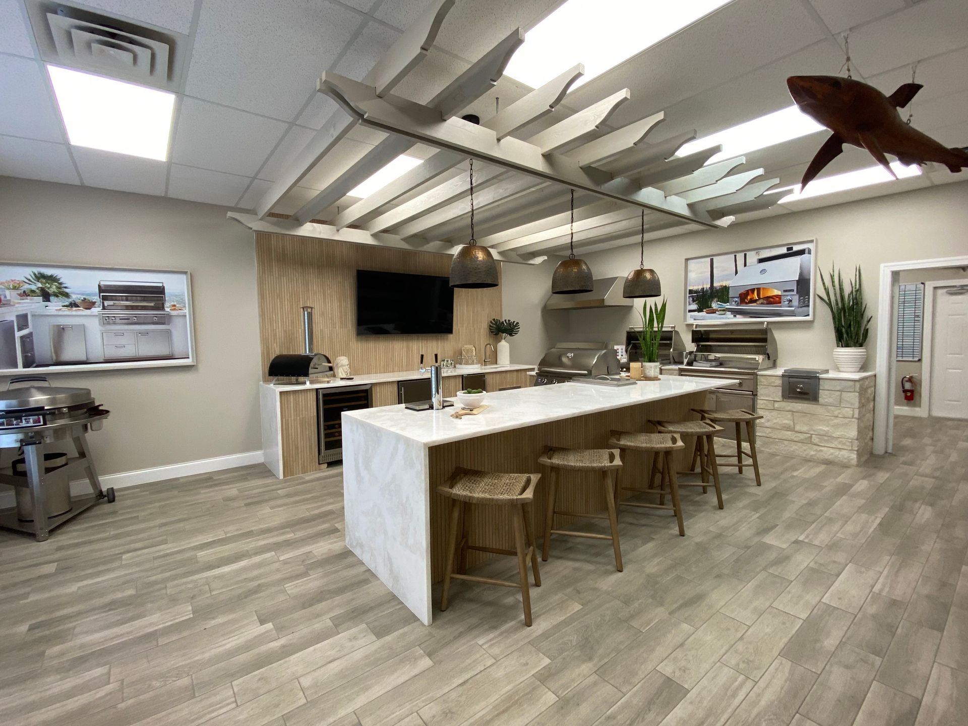 A kitchen with a long island , stools , a grill and a television.