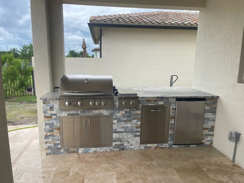 An outdoor kitchen with a grill and a dishwasher