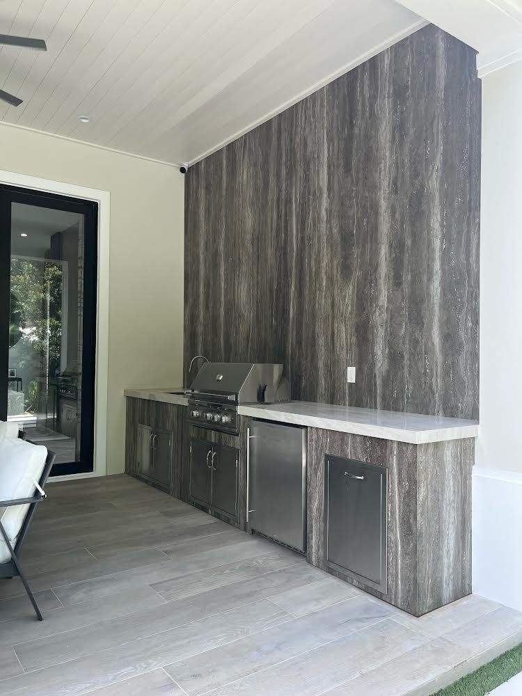 A patio with a grill and stainless steel cabinets.