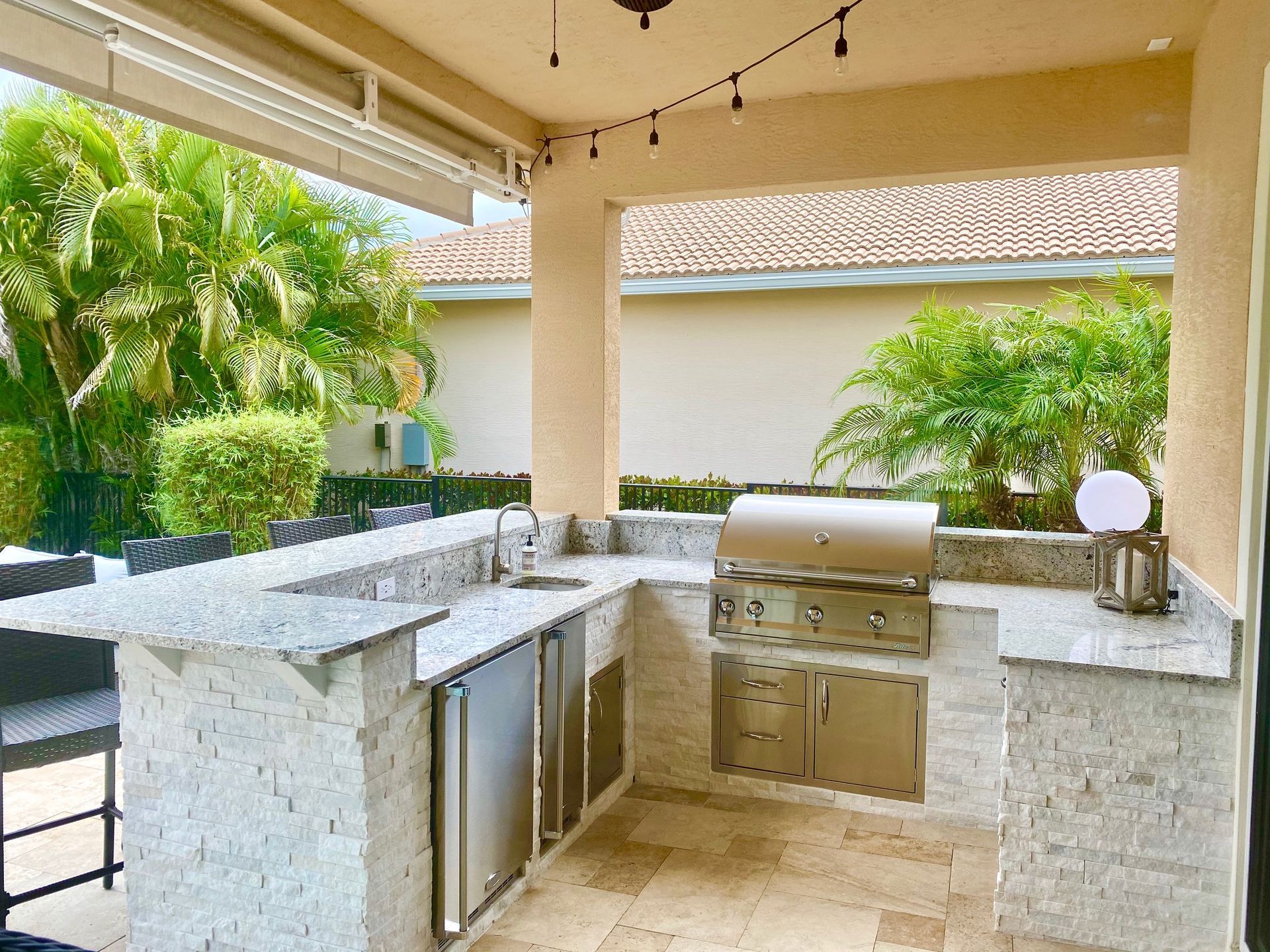 A large outdoor kitchen with a grill and a sink.