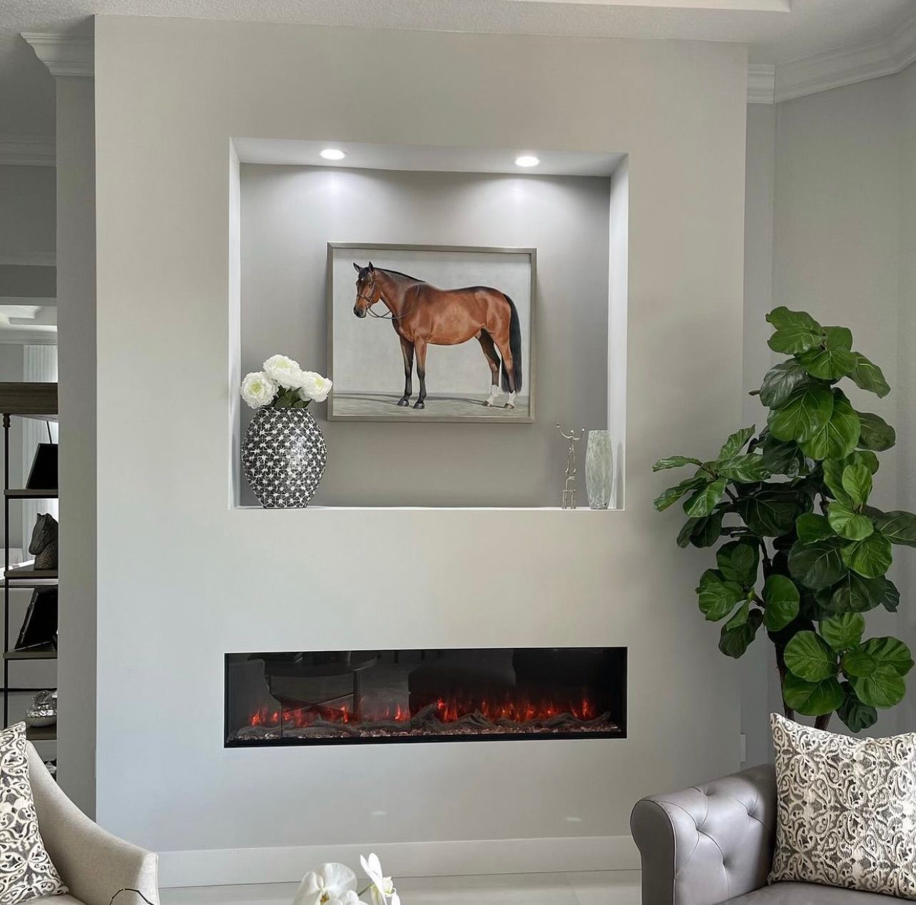 A living room with a fireplace and a picture of a horse on the wall