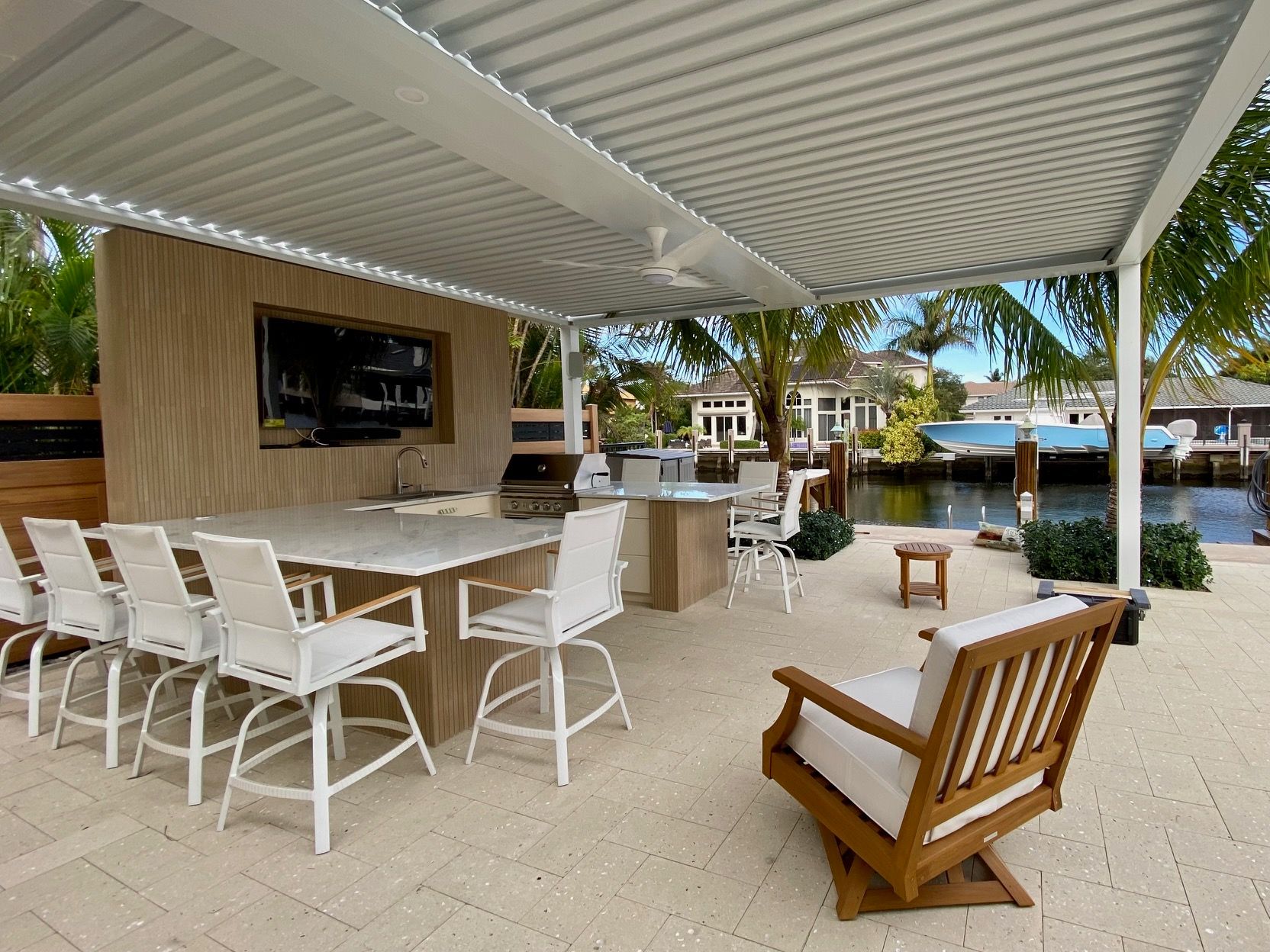 spacious patio with outdoor kitchen, dining area, and pergola in Deerfield Beach, FL.