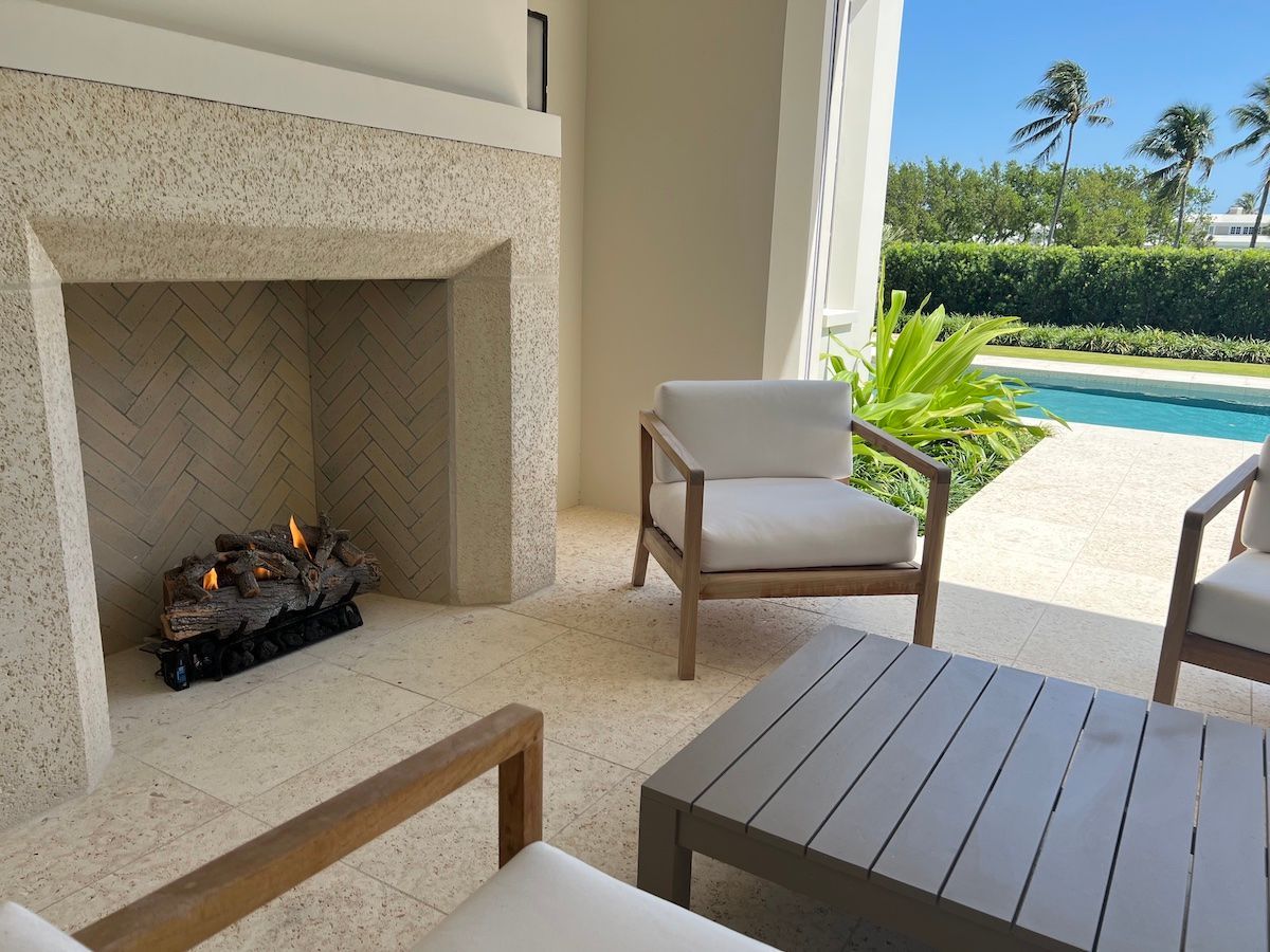 Outdoor fireplace with seating area next to a swimming pool in Boca Raton, FL.