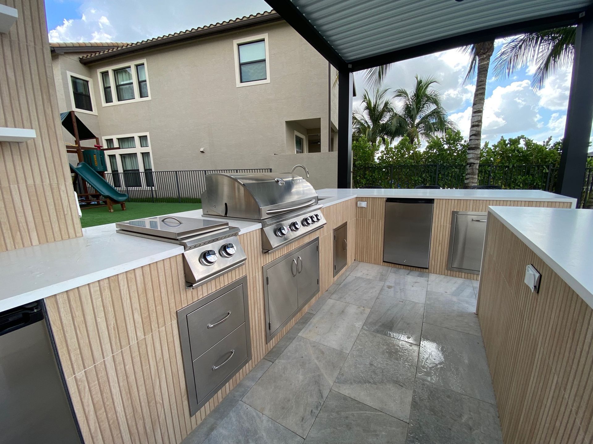 Outdoor kitchen with built-in grill and bar seating in Parkland, FL.