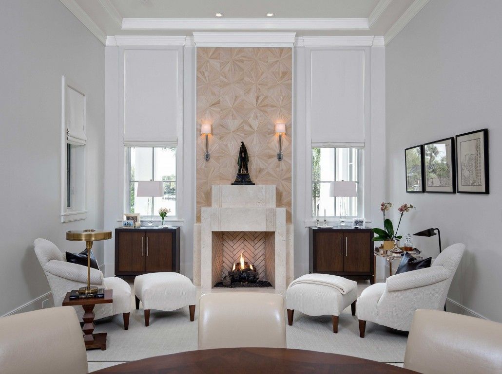A living room with a fireplace and chairs and ottomans