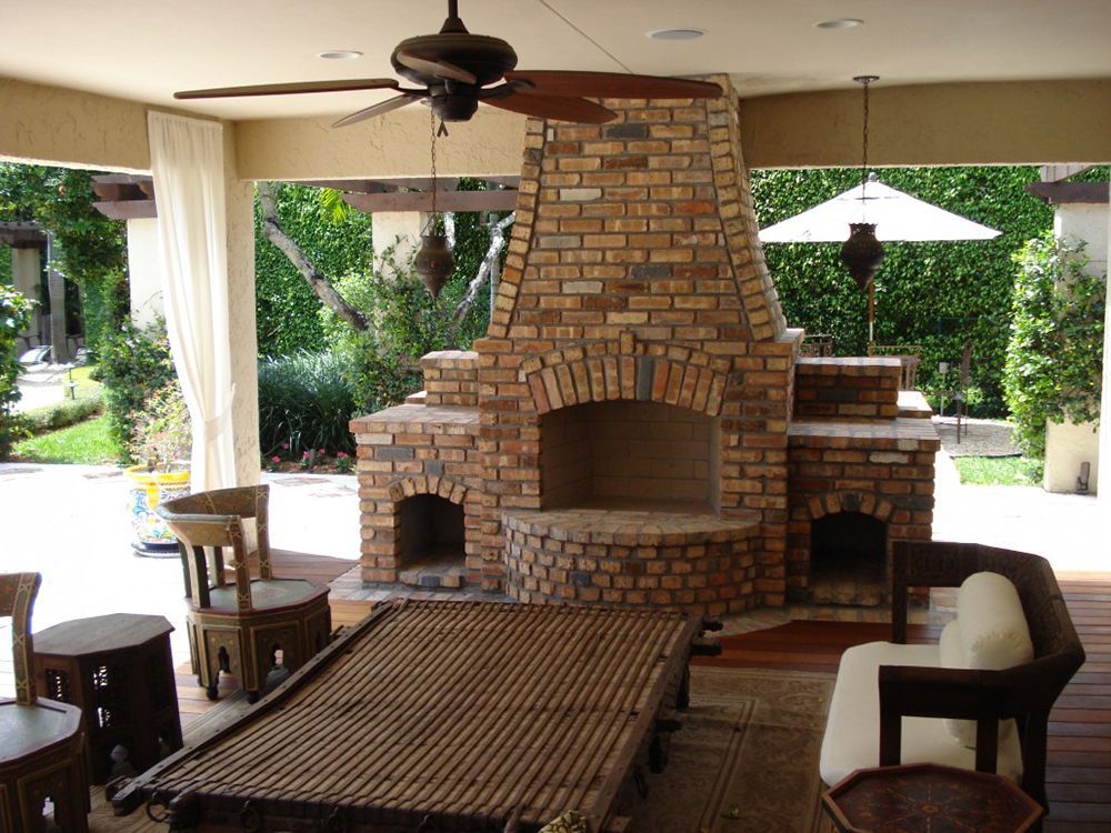 A living room with a brick fireplace and a ceiling fan