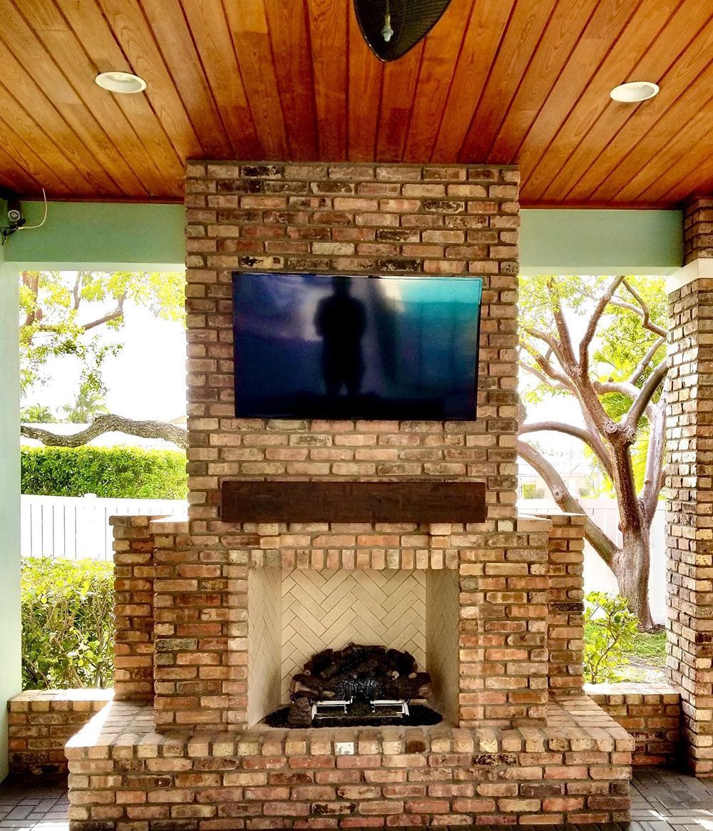 A brick fireplace with a flat screen tv mounted above it