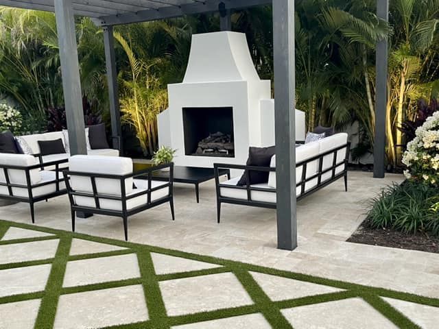 A patio with furniture and a fireplace under a pergola